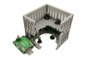 Grey 3D printed gothic ruins tabletop terrain shown with miniature soldiers and a vehicle for scale