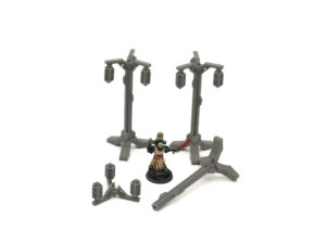 Grey 3D printed miniature street lamps for tabletop gaming, arranged with a painted miniature figure for scale