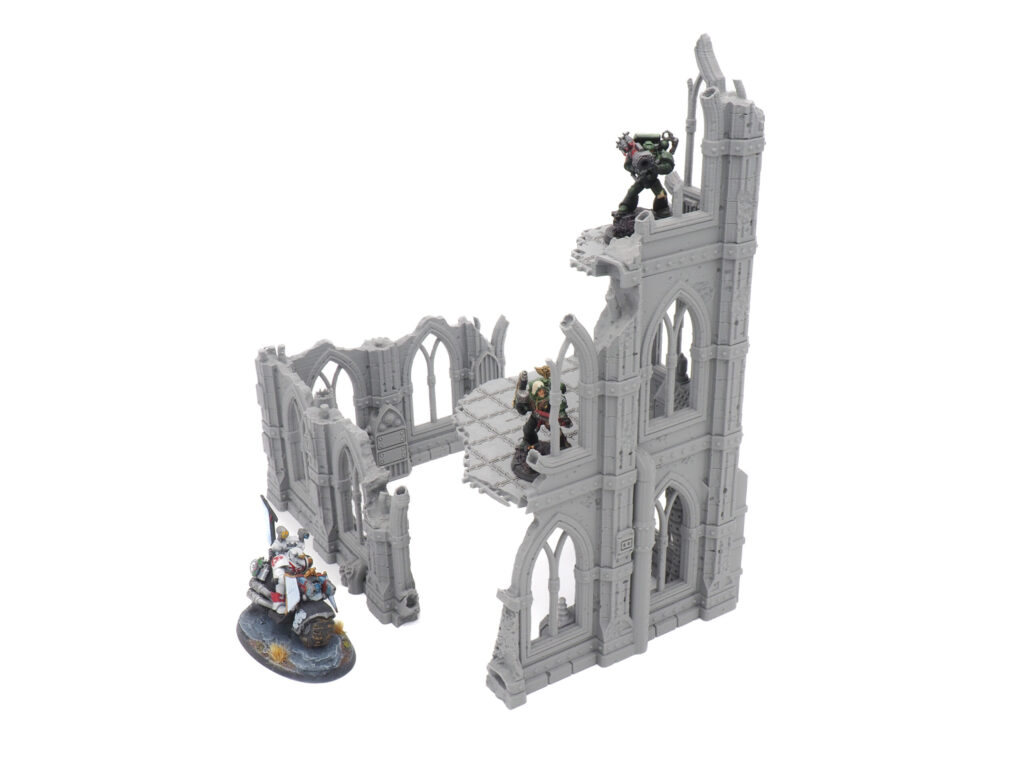 Grey 3D-printed gothic ruin miniature terrain with multiple levels, shown with sci-fi miniatures for scale