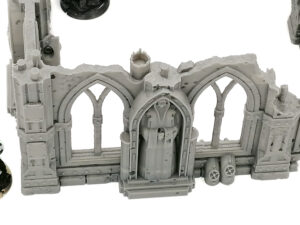 Grey 3D-printed tabletop terrain of a ruined gothic wall with arched windows and a central hooded statue