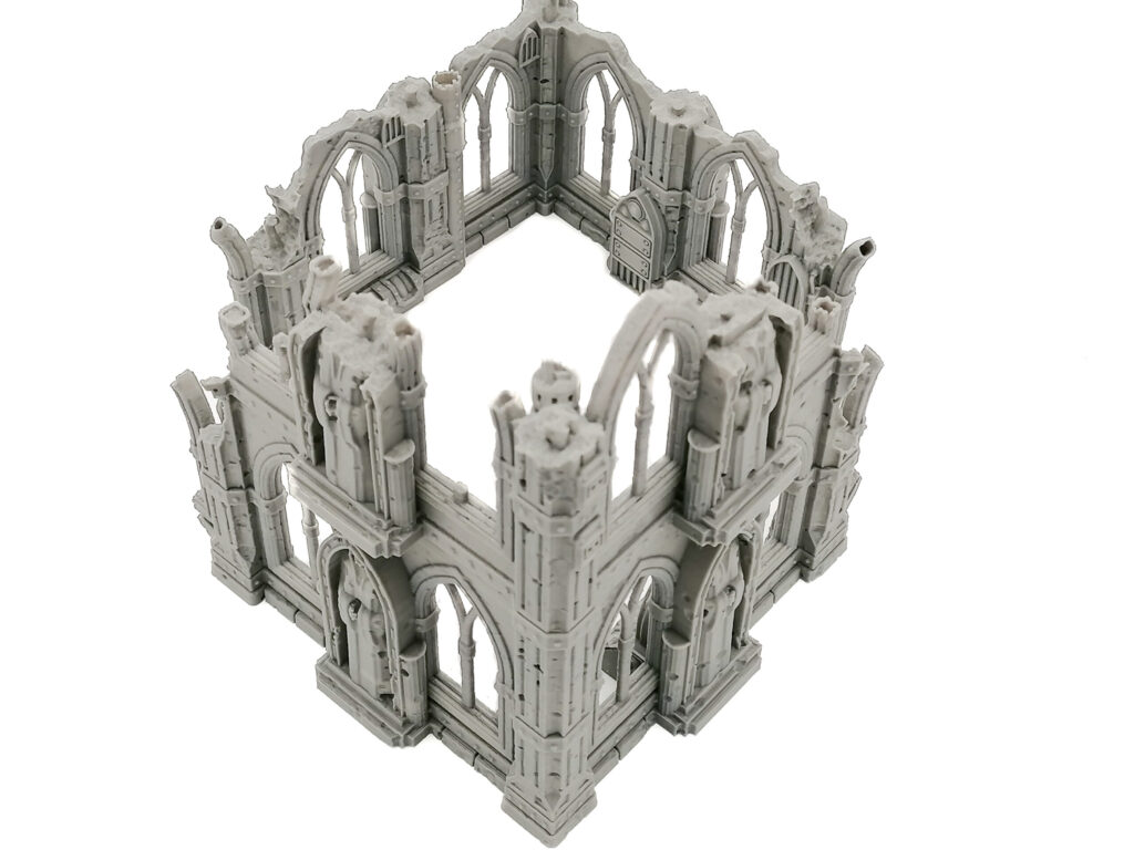 Grey 3D-printed miniature gothic ruin terrain for tabletop gaming, featuring arched windows and crumbling walls