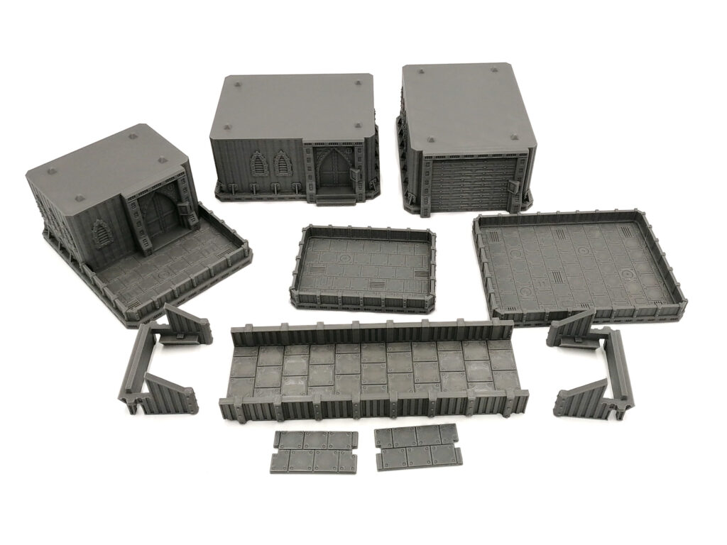 Grey 3D-printed modular tabletop terrain pieces, including gothic sci-fi buildings, platforms, and walkways