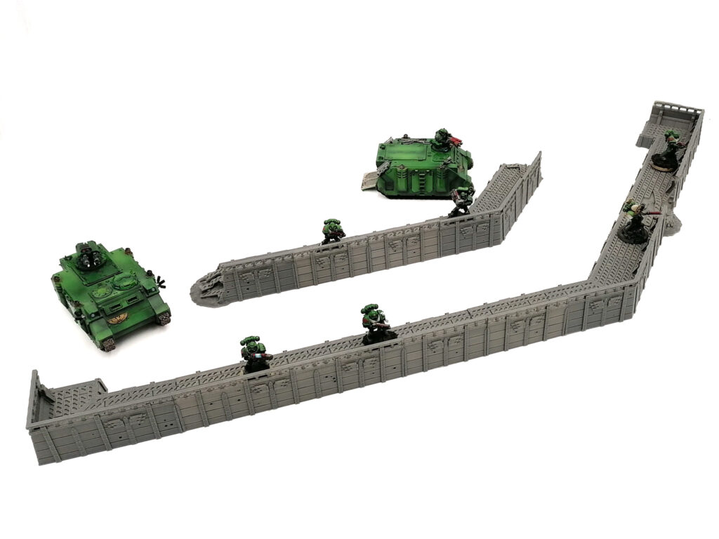 Grey 3D-printed sci-fi defensive walls for tabletop gaming, shown with green miniature soldiers and tanks