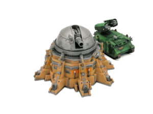 Miniature painted sci-fi turret bunker with a silver dome next to a green missile tank on a white background