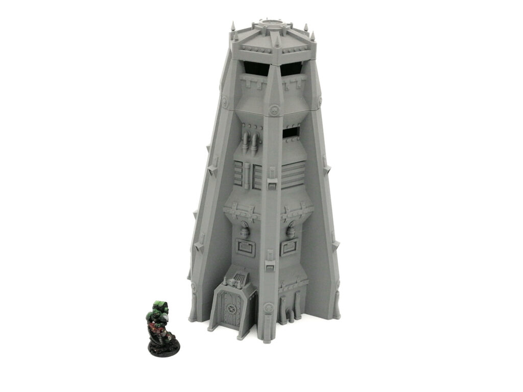 Grey 3D-printed sci-fi watchtower terrain model next to a miniature figure for scale