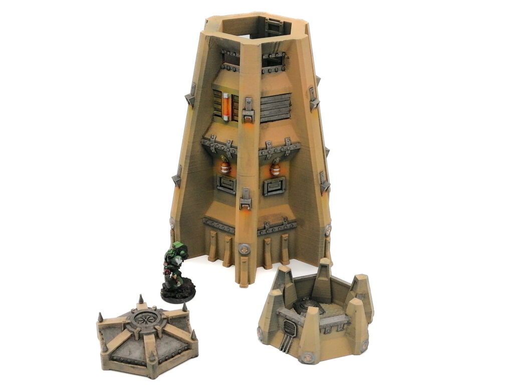 Painted 3D-printed sci-fi tower terrain pieces for tabletop gaming, shown with a miniature figure for scale
