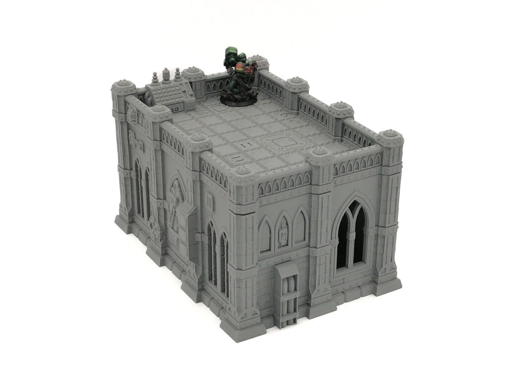 Grey 3D-printed gothic building miniature with a small painted figure on the flat rooftop