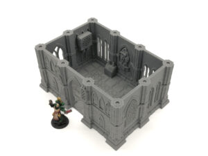 Grey 3D printed gothic building terrain for tabletop gaming, shown with a painted miniature figure for scale