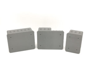 Three grey 3D-printed tabletop terrain pieces showing flat undersides with square connection sockets on a white background