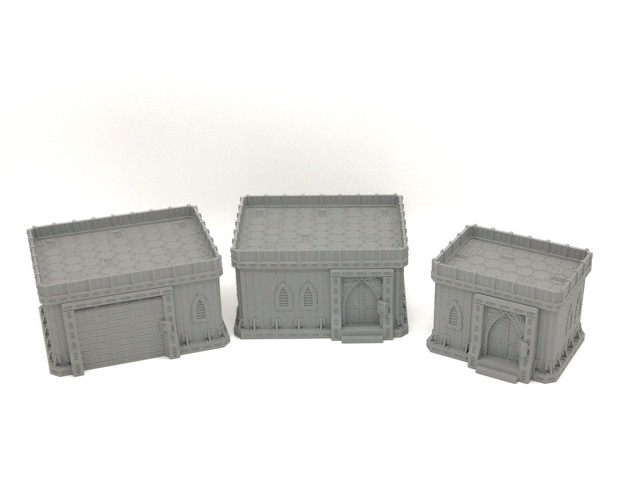 Three grey 3D-printed miniature gothic buildings for tabletop gaming terrain, isolated on a white background