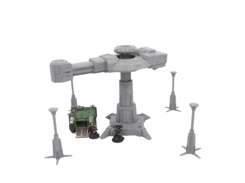 Grey 3D printed tabletop sci-fi tower and four pillars, shown with painted miniature figures for scale