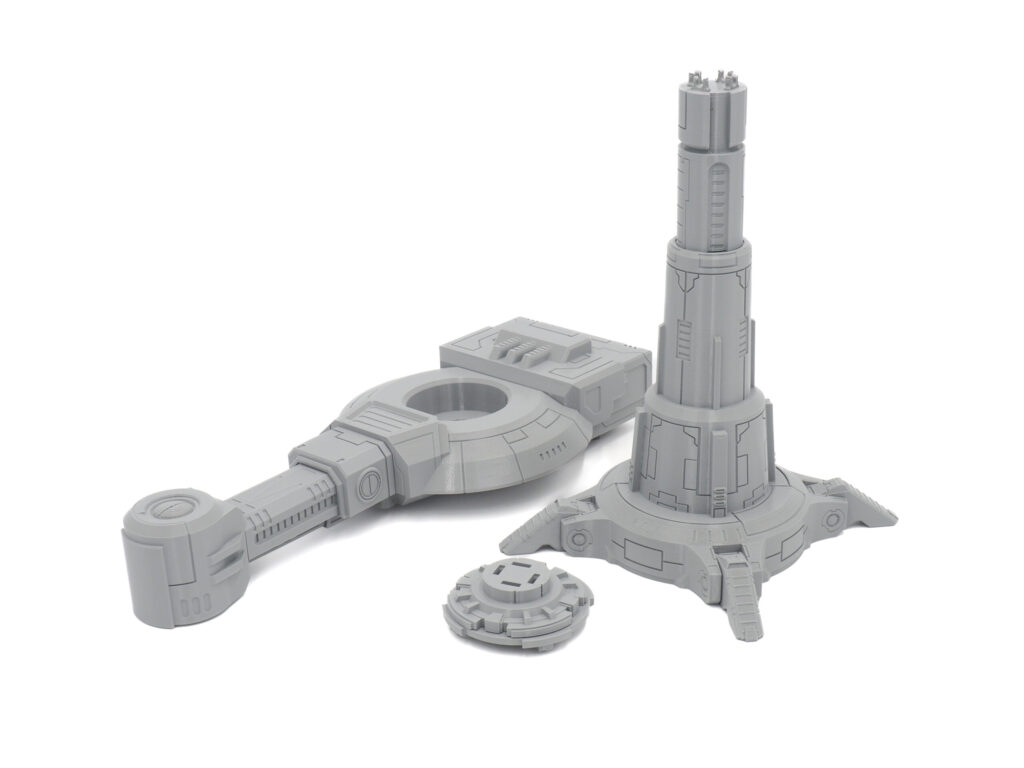 Grey 3D-printed sci-fi tabletop terrain components, featuring a tall tower, a console structure, and a circular hatch