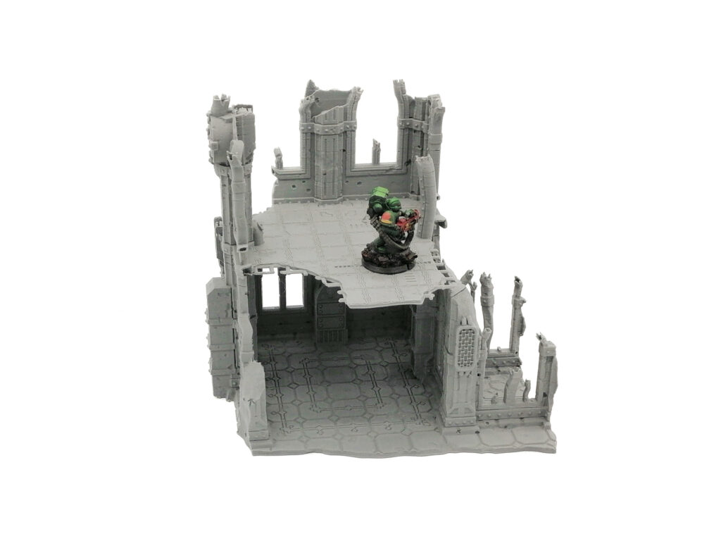 Grey 3D-printed sci-fi ruined building terrain, shown with a painted miniature figure for scale