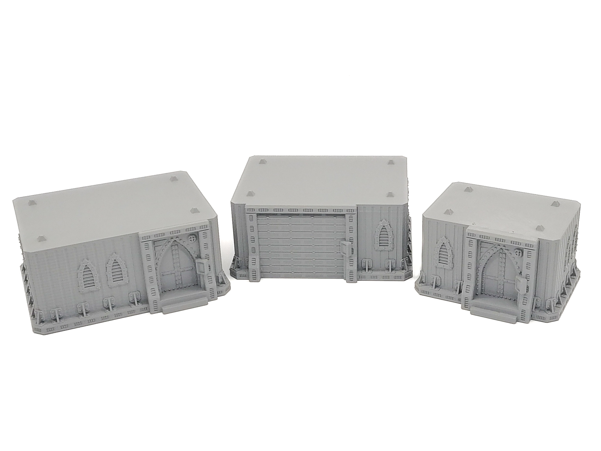 Three unpainted grey 3D-printed gothic miniature buildings for tabletop wargaming terrain