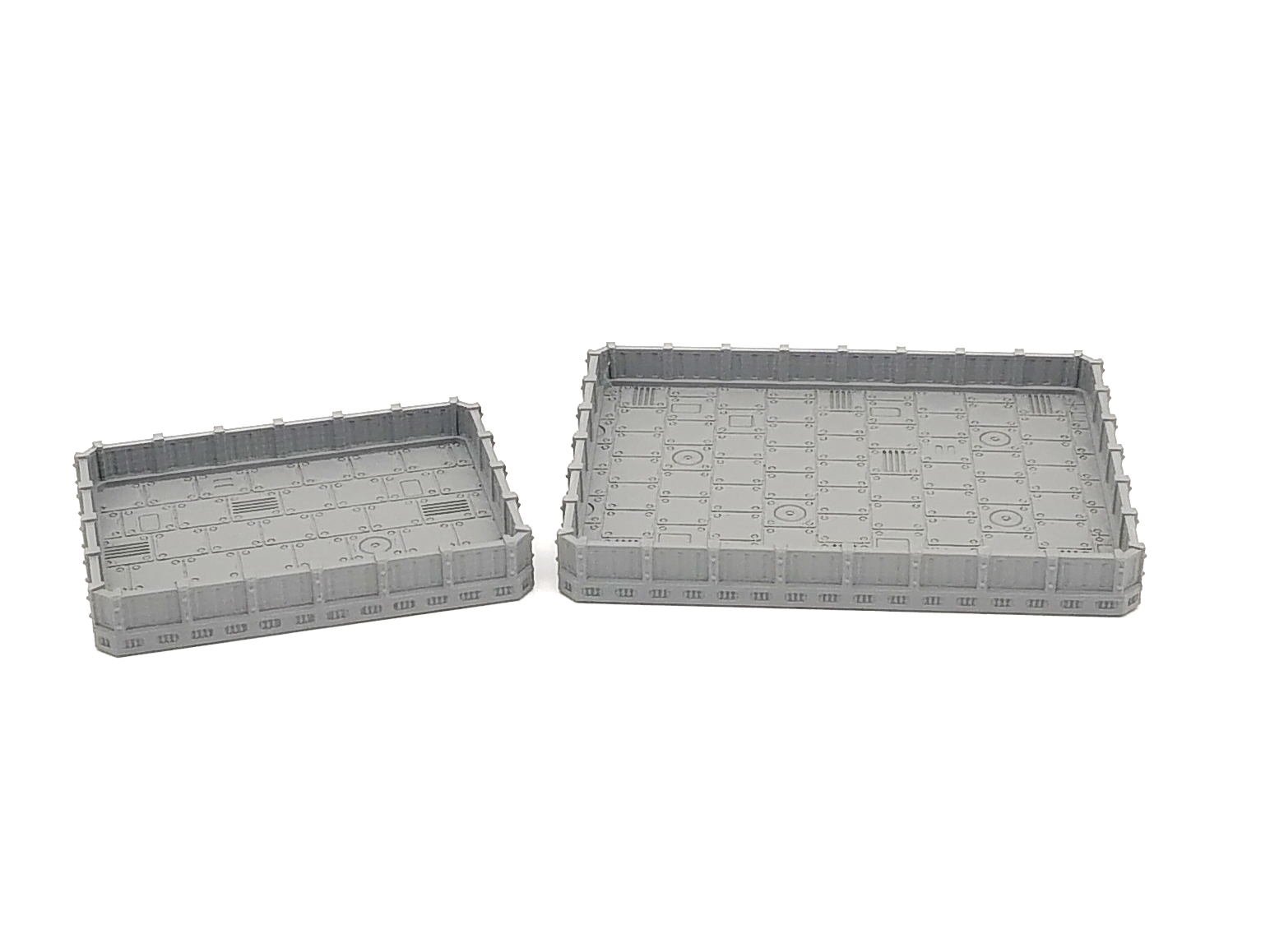 Two grey 3D-printed sci-fi miniature terrain trays with textured industrial floor panels, shown in small and large