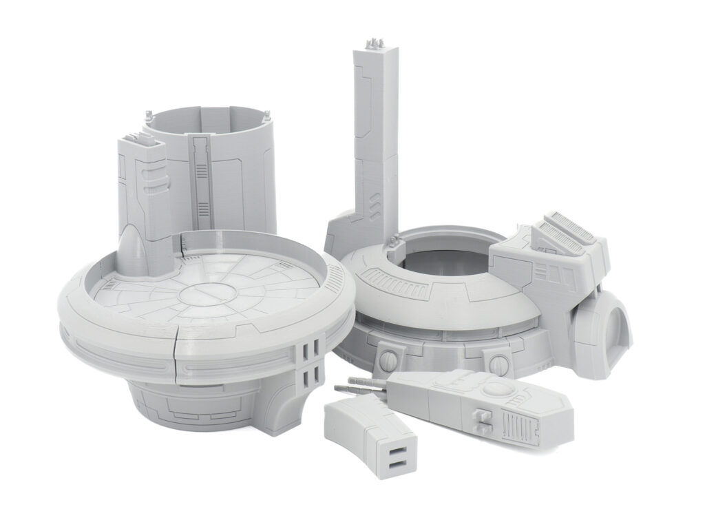 Grey 3D-printed modular sci-fi terrain components, including a circular landing pad, for tabletop gaming