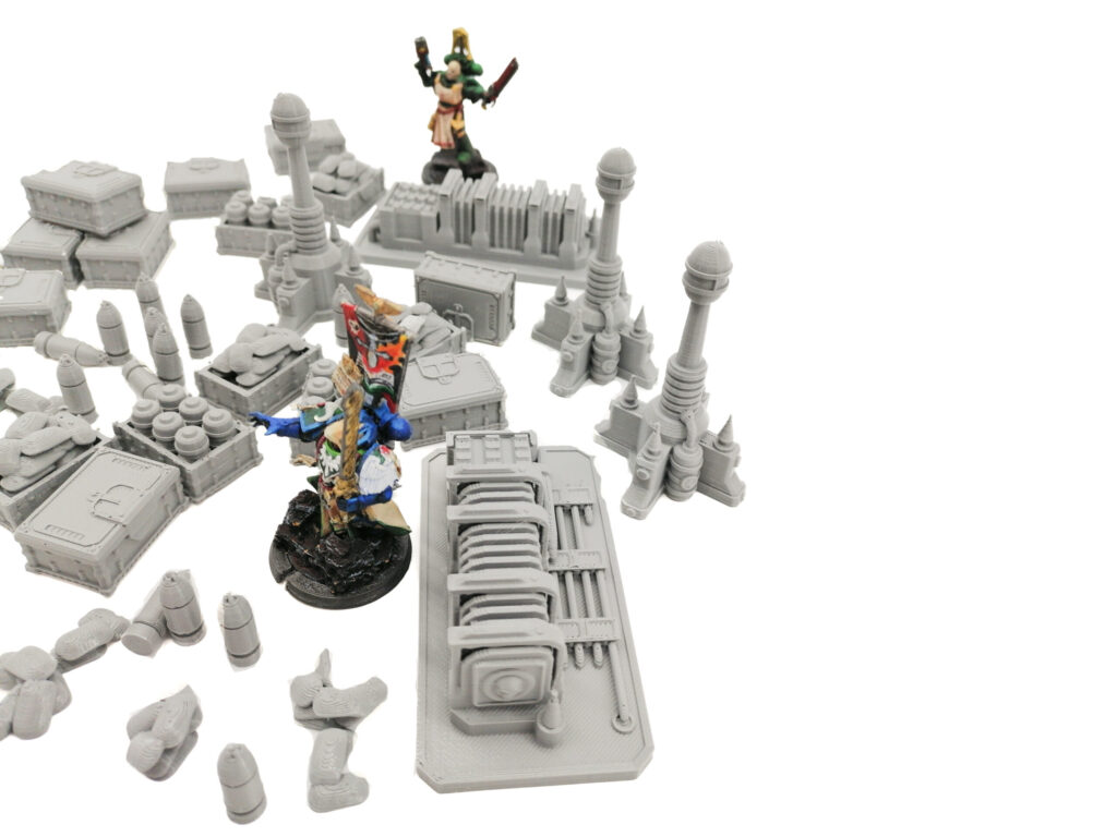 Unpainted grey 3D-printed sci-fi tabletop terrain pieces shown with two painted miniature figures