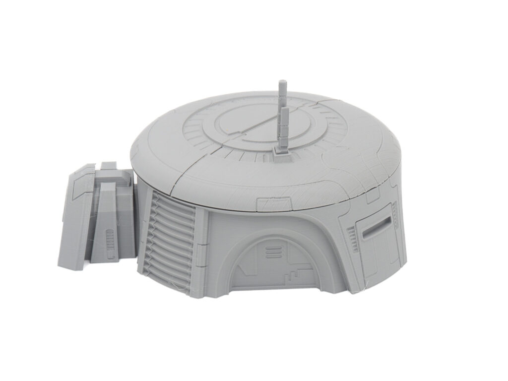 Grey 3D-printed sci-fi bunker miniature with a circular domed roof and antenna, on a white background
