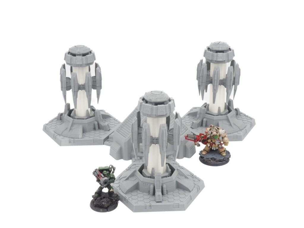 Three 3D-printed grey sci-fi power generators for tabletop gaming, shown with two painted miniatures for scale