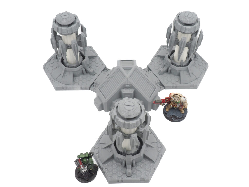Grey 3D-printed sci-fi tabletop gaming terrain featuring three generator towers, shown with miniature figures for scale