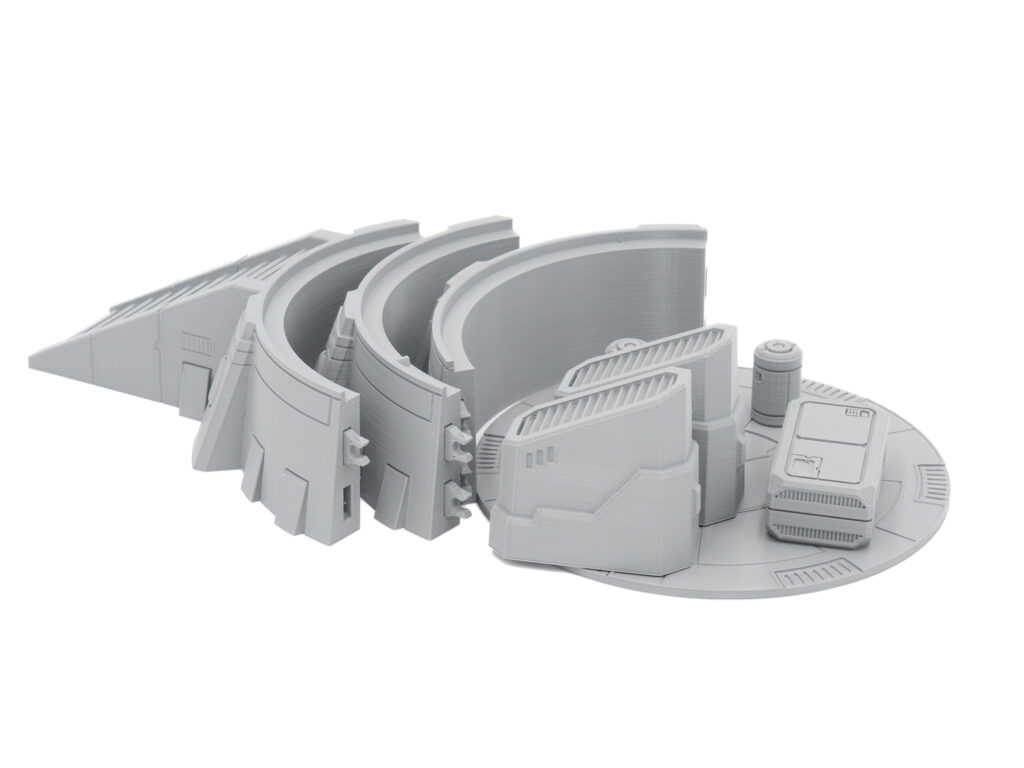 Grey 3D-printed sci-fi tabletop gaming terrain featuring modular curved walls, a ramp, and crates