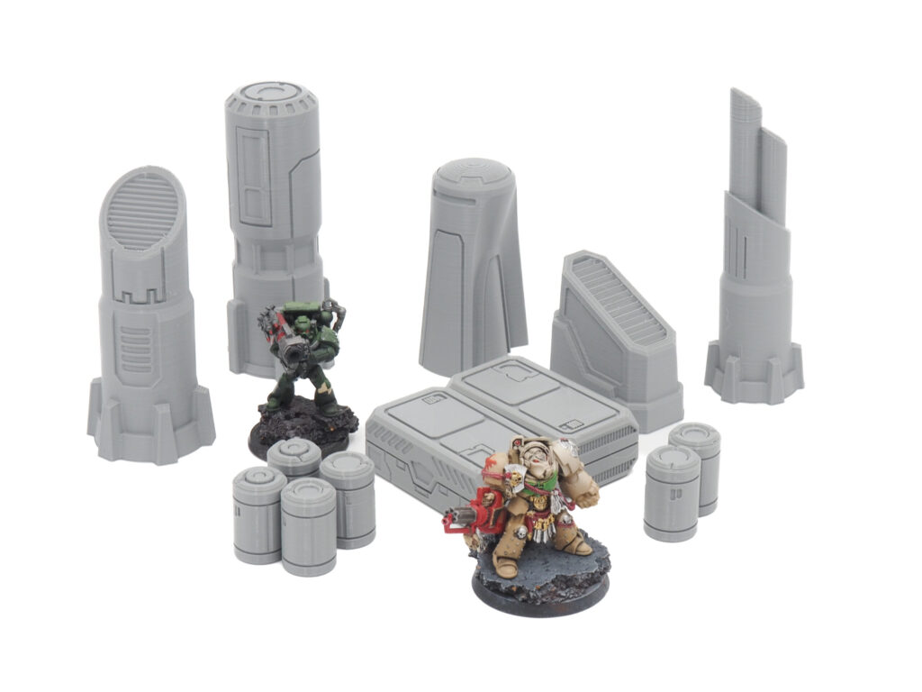 Unpainted grey 3D printed sci-fi tabletop gaming terrain set, displayed with painted miniature figures for scale