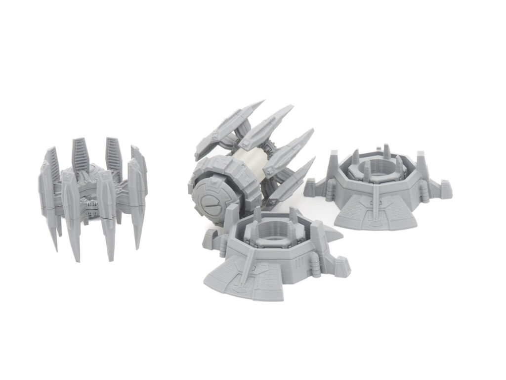 Unpainted grey 3D-printed sci-fi generator and power pylon terrain miniatures on a white background