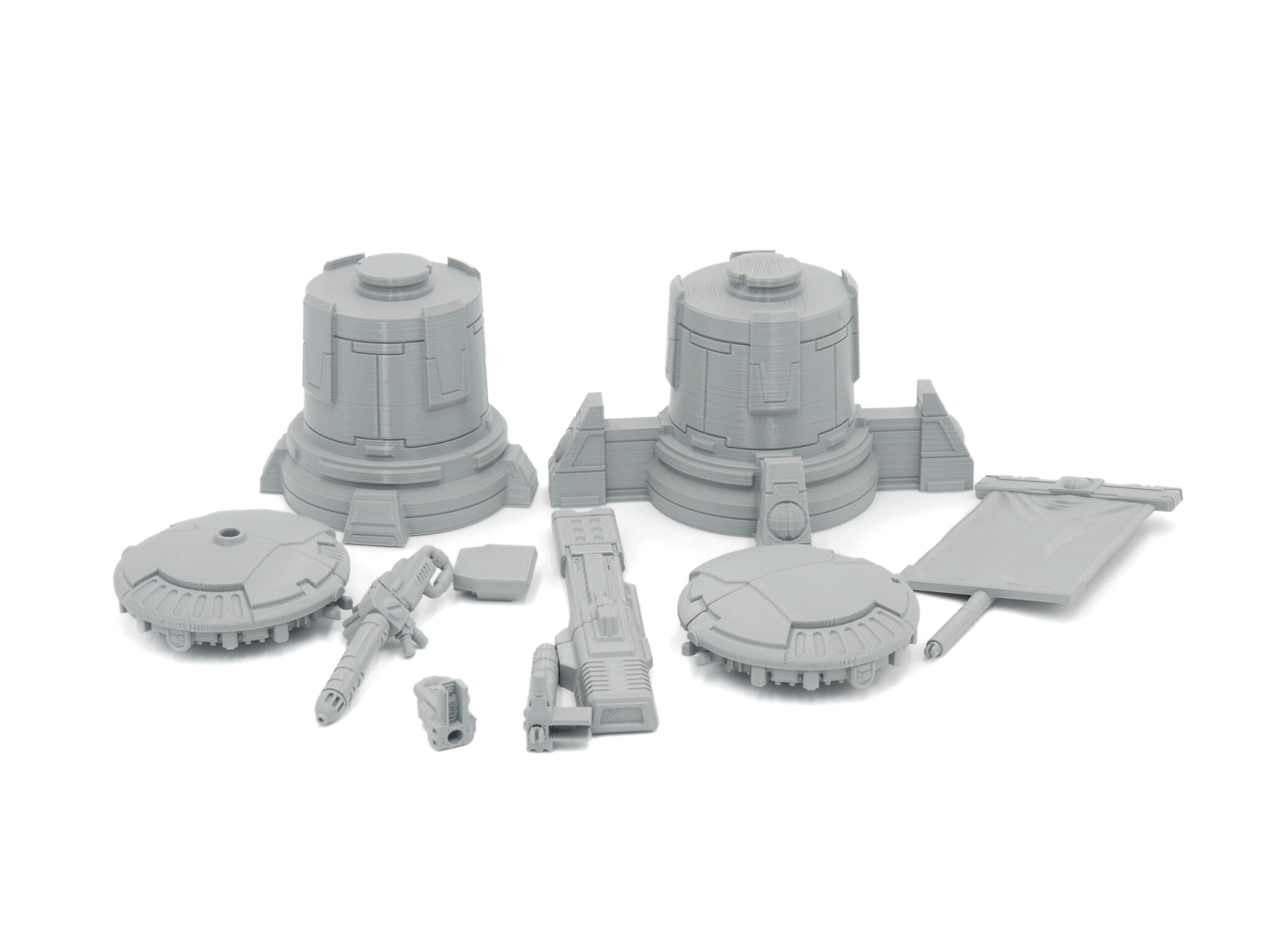 Grey 3D-printed sci-fi miniature terrain and weapon parts laid out on a white background