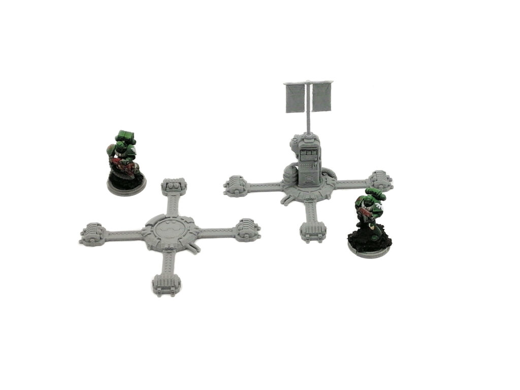 Grey 3D-printed sci-fi tabletop terrain pieces shown alongside painted miniature soldiers for scale