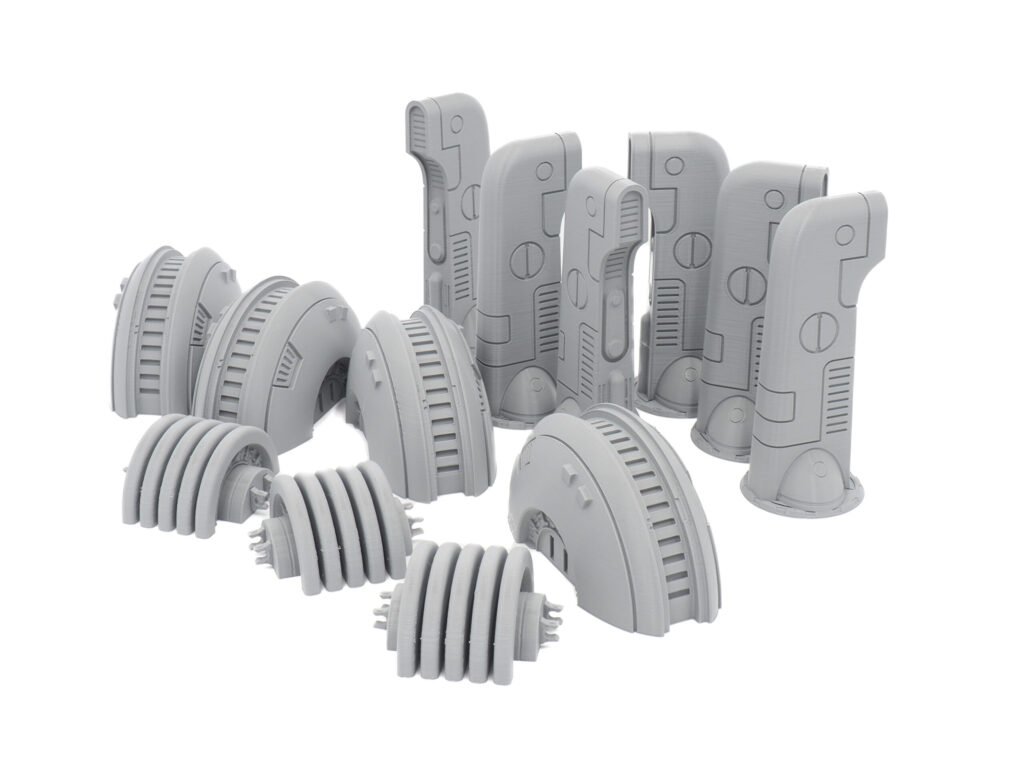 Grey 3D-printed sci-fi miniature terrain pieces, including pillars and power generators, on a white background