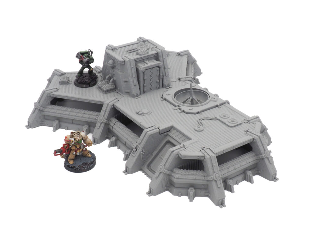 Unpainted grey 3D-printed sci-fi bunker terrain with painted miniature figures for scale