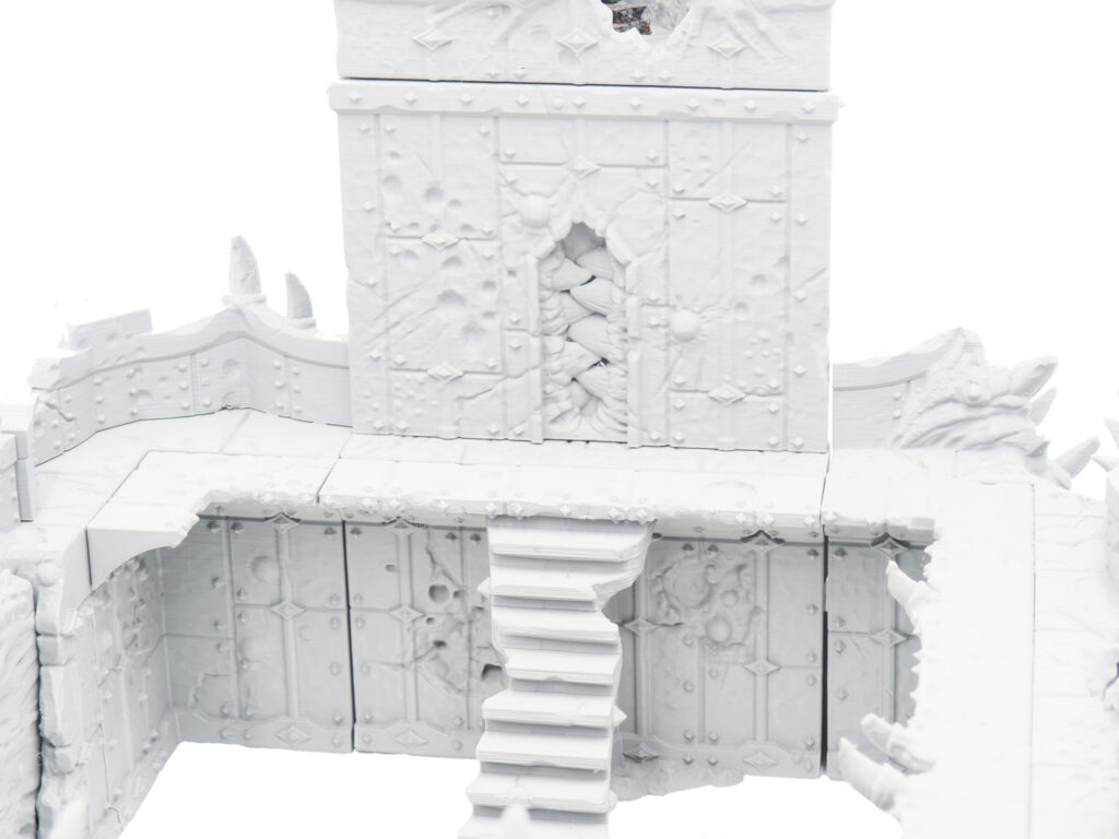3D-printed white miniature fantasy fortress wall with a tower, stairs, and detailed stone textures