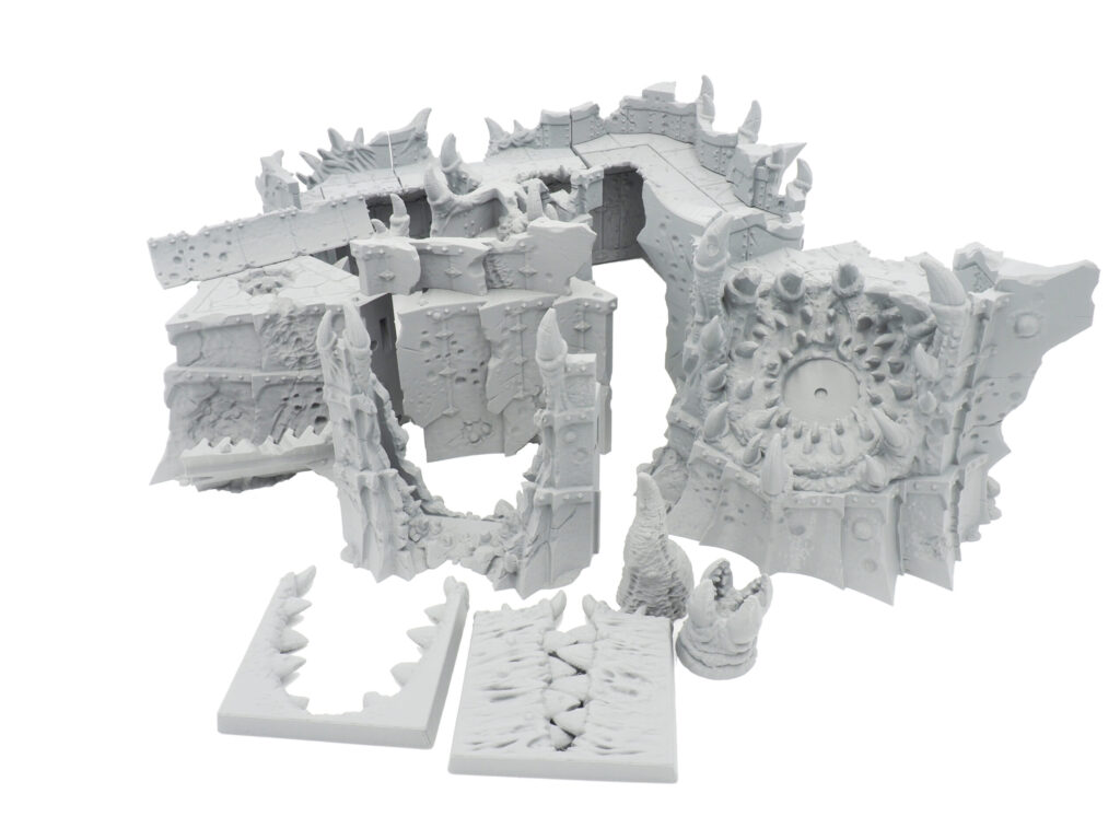 Unpainted grey 3D-printed modular tabletop terrain set featuring spiked demonic walls and ruins