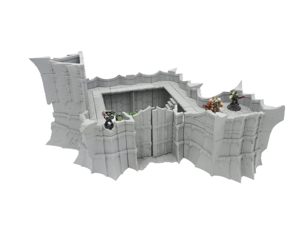 Modular 3D printed grey fortress wall terrain for tabletop gaming, with miniature figures on the ramparts for scale