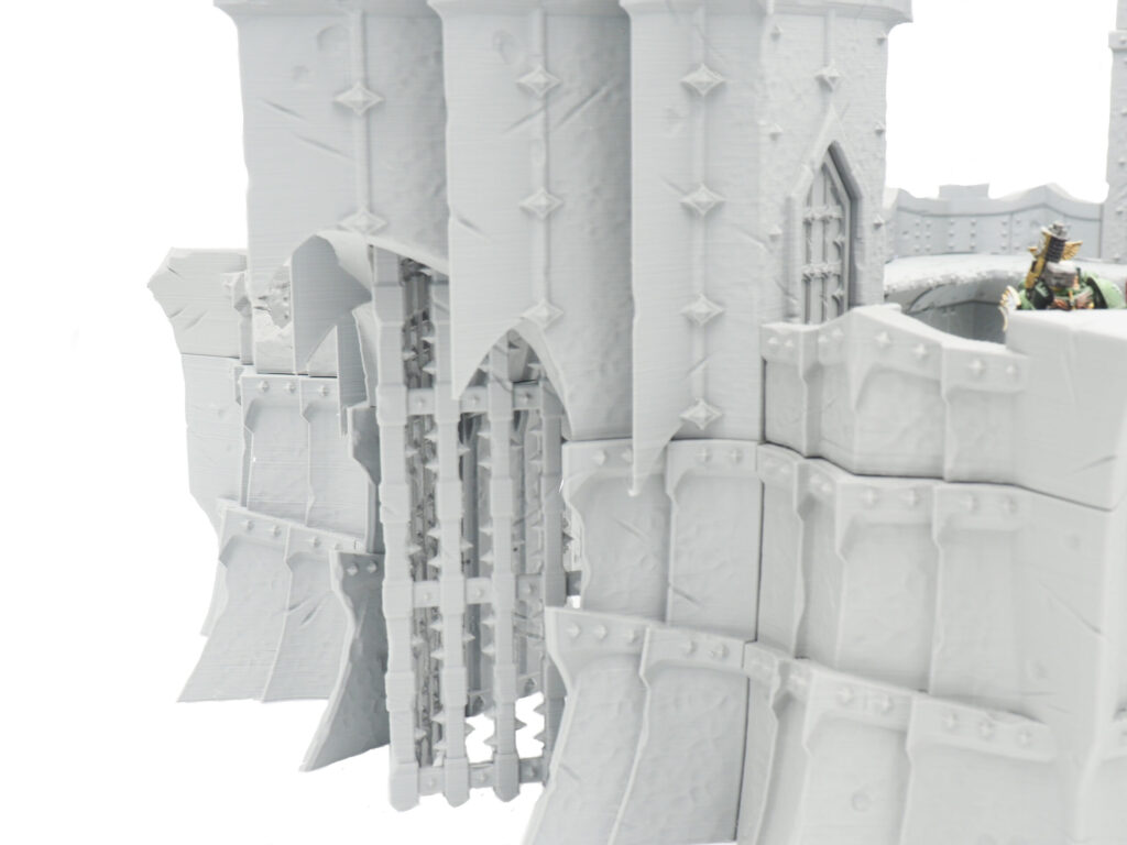 3D-printed grey fantasy castle gatehouse model with a portcullis, designed for tabletop wargaming