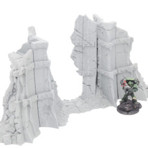 Grey 3D-printed ruined wall terrain for tabletop gaming, shown next to a painted miniature figure for scale
