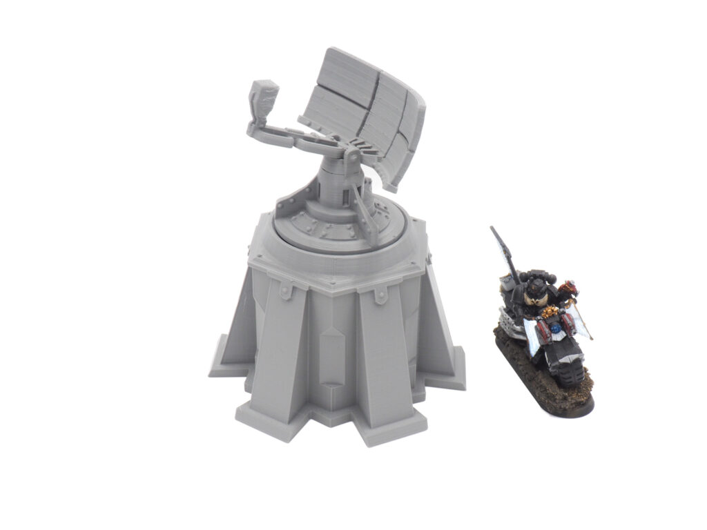 Grey 3D-printed sci-fi radar tower model next to a painted gaming miniature for scale on a white background