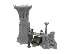 Grey 3D-printed gothic tower and ruins terrain, shown with miniature gaming figures and a vehicle for scale