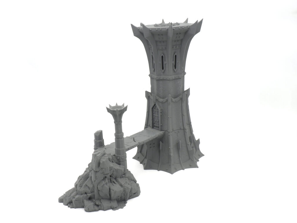 Grey 3D-printed miniature fantasy tower with a bridge leading to a rocky outcrop, designed for tabletop gaming