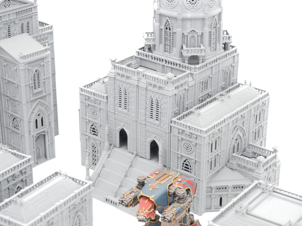 Grey 3D-printed gothic cathedral tabletop terrain shown with a painted miniature for scale