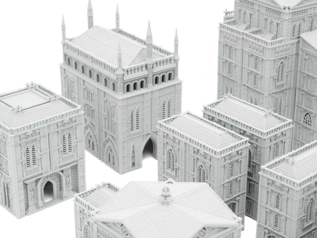 Grey 3D-printed miniature gothic buildings with intricate details, designed for tabletop wargaming terrain