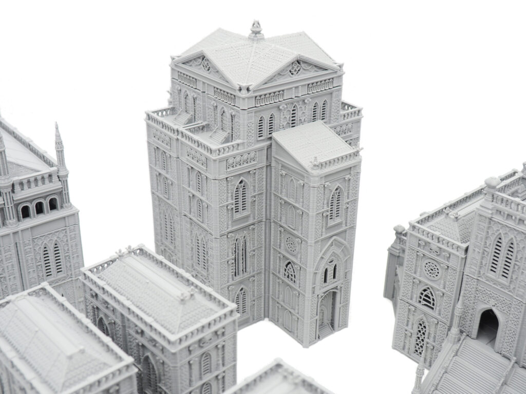 Grey 3D-printed miniature gothic cathedral buildings for tabletop gaming, on a white background