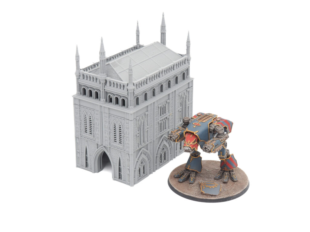 Grey 3D printed gothic building terrain shown next to a painted tabletop sci-fi mech miniature for scale