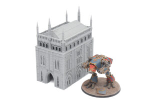 Grey 3D printed gothic building terrain shown next to a painted tabletop sci-fi mech miniature for scale