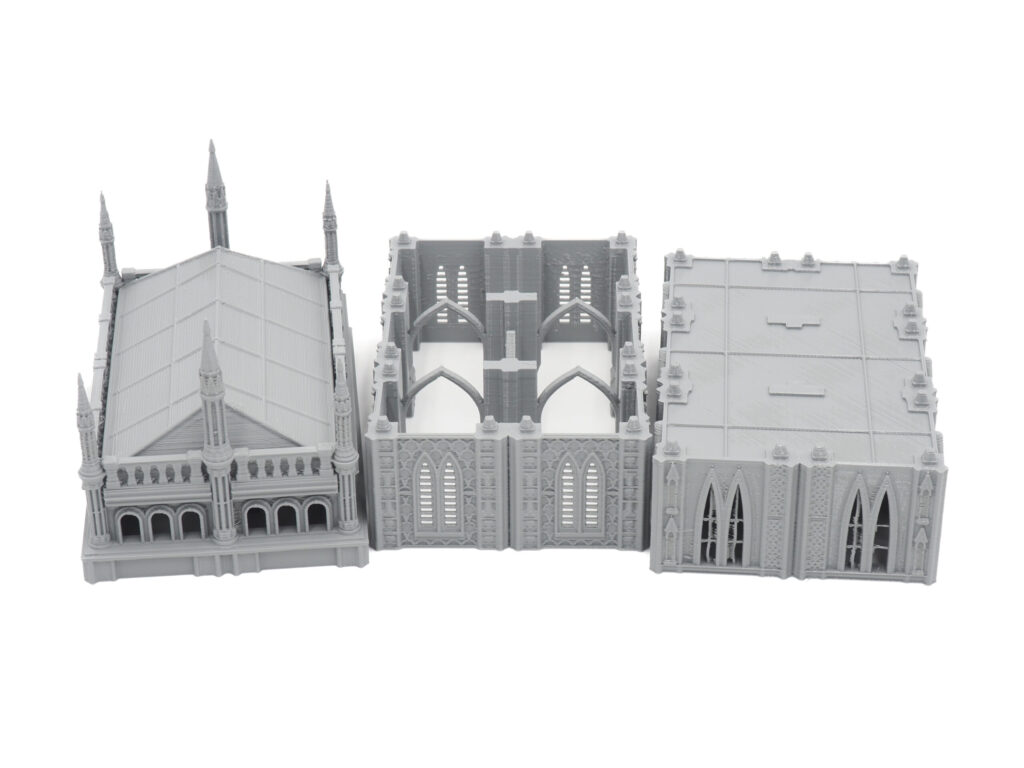 Three grey 3D-printed gothic modular building terrain pieces for tabletop wargaming on a white background