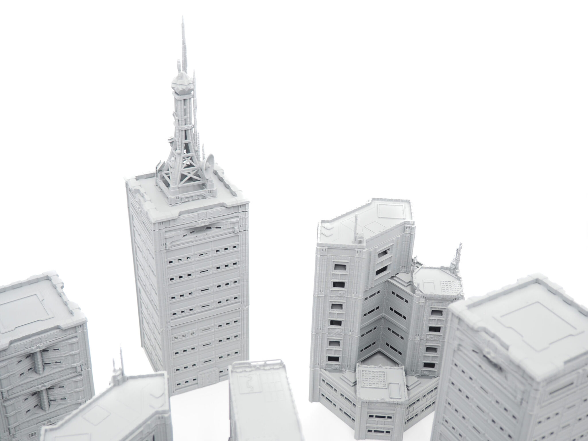 Grey 3D-printed miniature skyscrapers and buildings for tabletop gaming terrain, shot on a white background