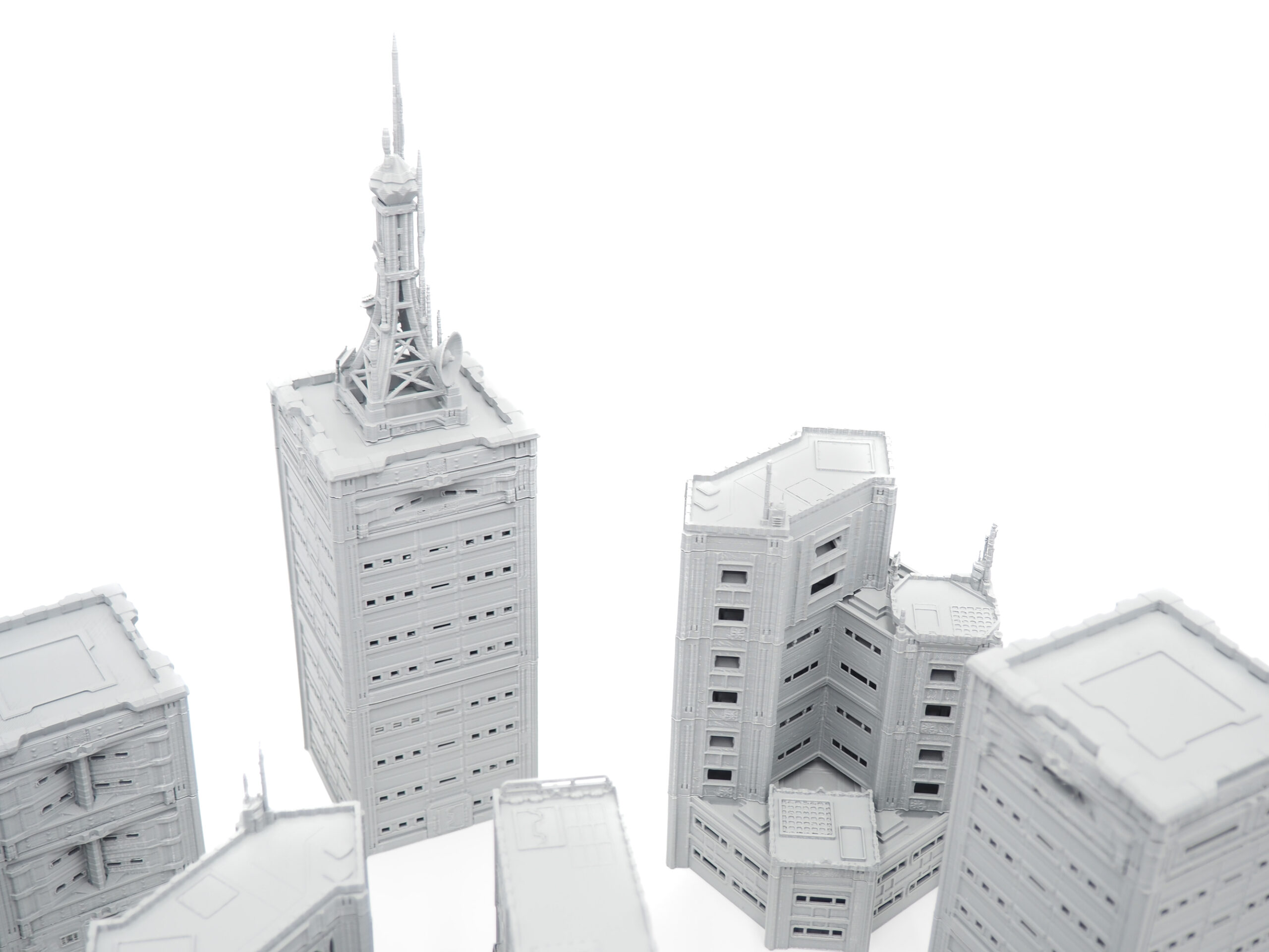 Grey 3D-printed miniature skyscrapers and buildings for tabletop gaming terrain, shot on a white background