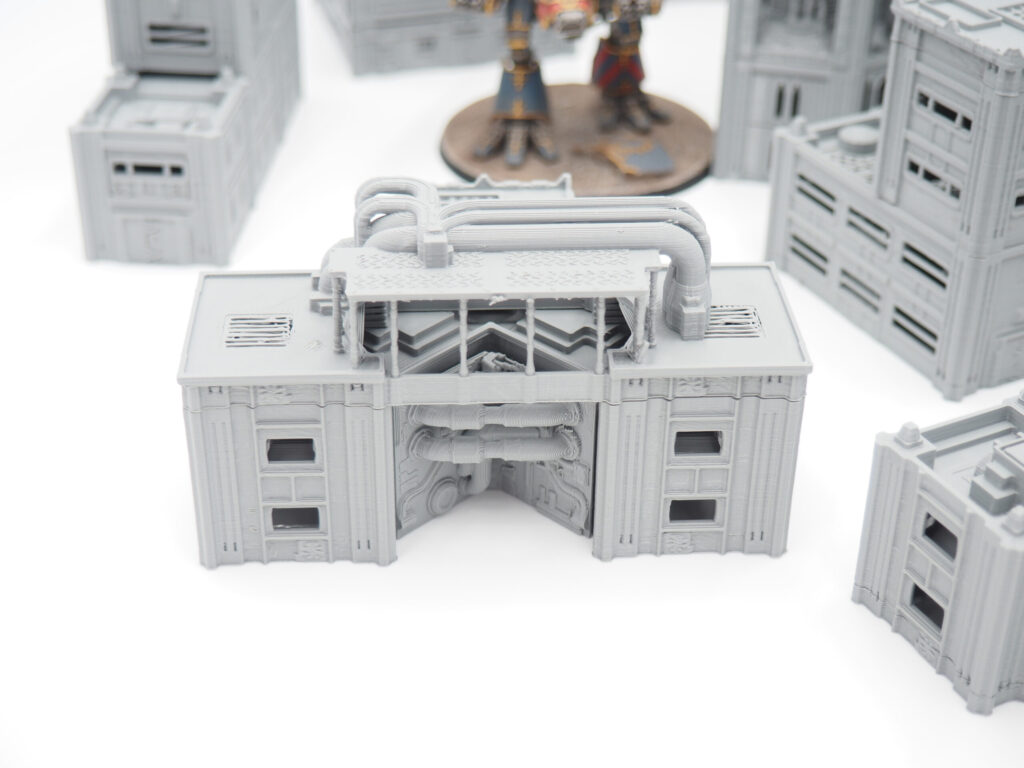 Grey 3D-printed industrial building terrain piece with exposed pipes for tabletop wargaming