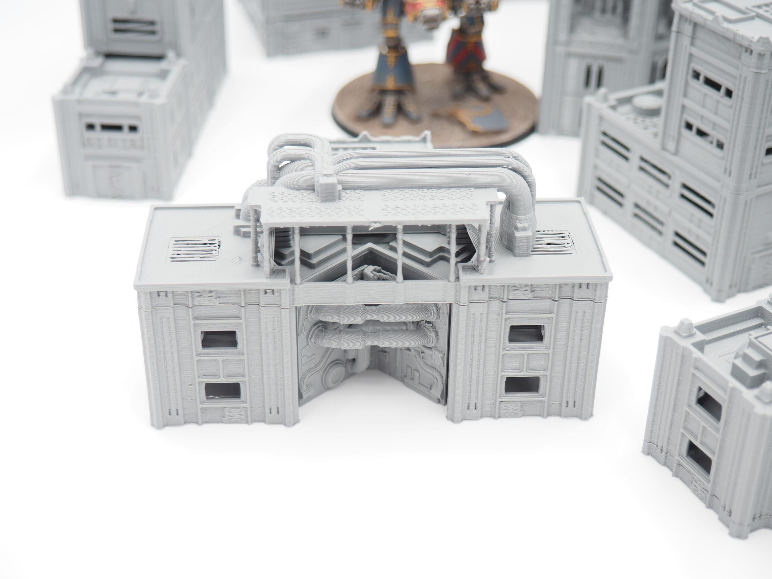 Grey 3D-printed industrial building terrain piece with exposed pipes for tabletop wargaming