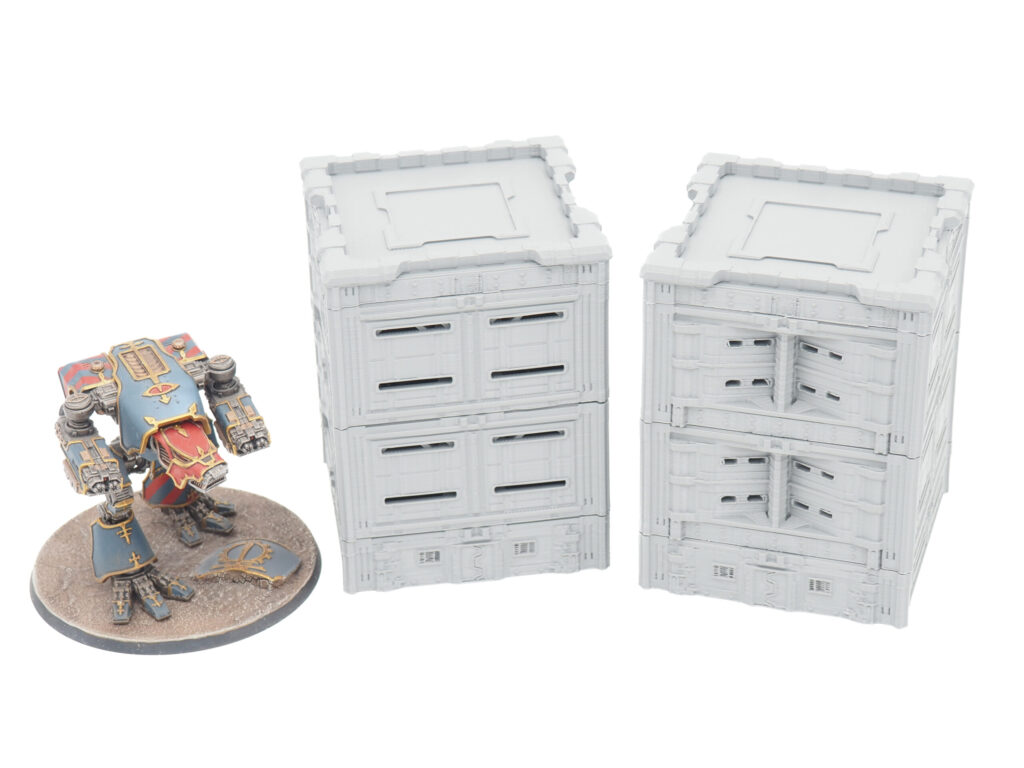 Two grey 3D-printed modular sci-fi buildings shown alongside a painted mech figurine for size comparison